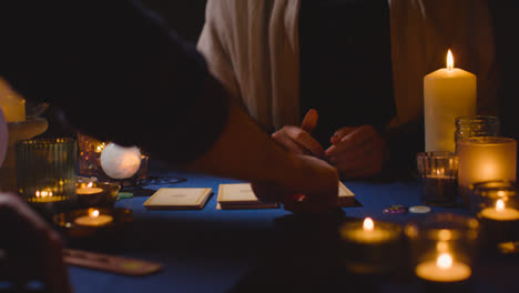 Nahaufnahme-Einer-Frau,-Die-Einem-Mann-Am-Tisch-Bei-Kerzenschein-Tarotkarten-Vorliest-2